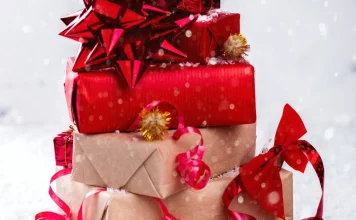 The 54 Best Bulk Christmas Gifts for 2026, Curated By Experts Stack of wrapped Christmas gifts with red bows