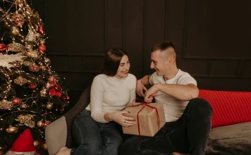 Couple exchanging Christmas gifts by the tree