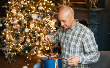 37 Best Christmas Gifts for Men, From Tech to Hobbies Man unwrapping a Christmas gift at home