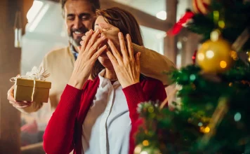 33 Best Christmas Gifts for Wife (Romantic, Luxe and Useful) Husband surprising his wife with a Christmas gift
