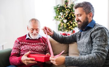 What Do You Get a Dad Who Says He Doesn’t Want Anything? Adult son helping his father open a Christmas gift