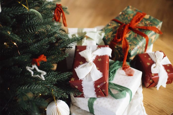 festively wrapped christmas gifts under a christmas tree with ornaments on it