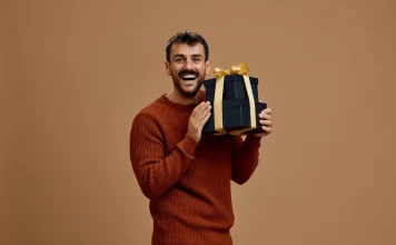 60 Great Gifts for Men Who Have Everything, Curated By Experts Smiling man holding a stack of gift boxes