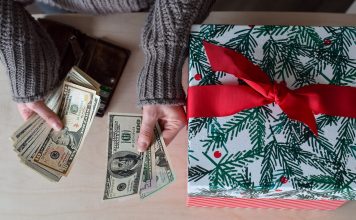 How Much Should You Spend on a Secret Santa Gift? Person counting cash next to a wrapped Christmas gift